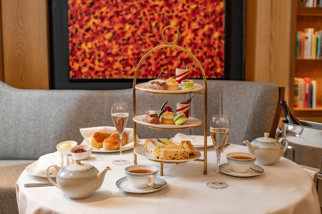 Middle Eight - Covent Garden - Preferred Hotels And Resorts London Exterior photo The photo shows an elegant afternoon tea setup on a white tablecloth. At the center, there is a multi-tiered stand displaying a variety of pastries and desserts, including cakes and colorful sweets. Surrounding the stand are teapots and teacups, read