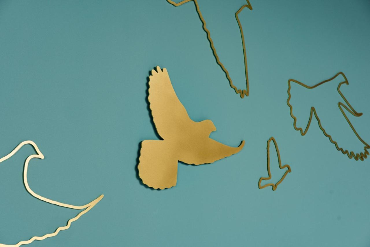 Middle Eight - Covent Garden - Preferred Hotels And Resorts London Exterior photo The photo shows a collection of metallic gold bird silhouettes against a solid turquoise background. The birds are depicted in various positions and styles, showcasing different species and flight postures. Some silhouettes are more detailed, while o
